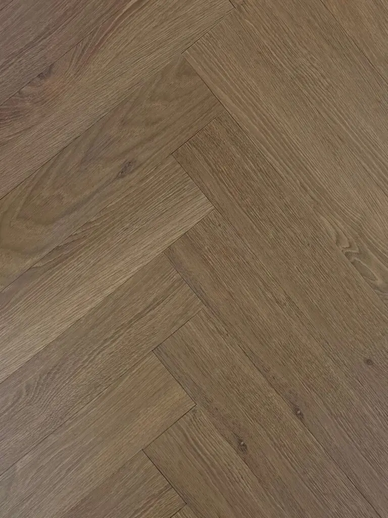 English Oak LVT herringbone flooring – photograph of the actual product laid in a herringbone pattern, mid-brown oak